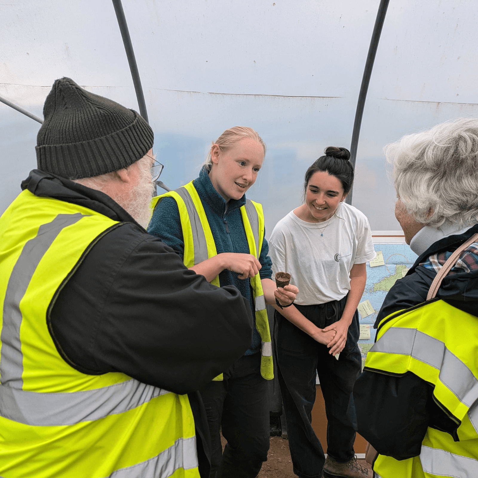 Two members of Project Seagrass staff stand talking to two members of the community.