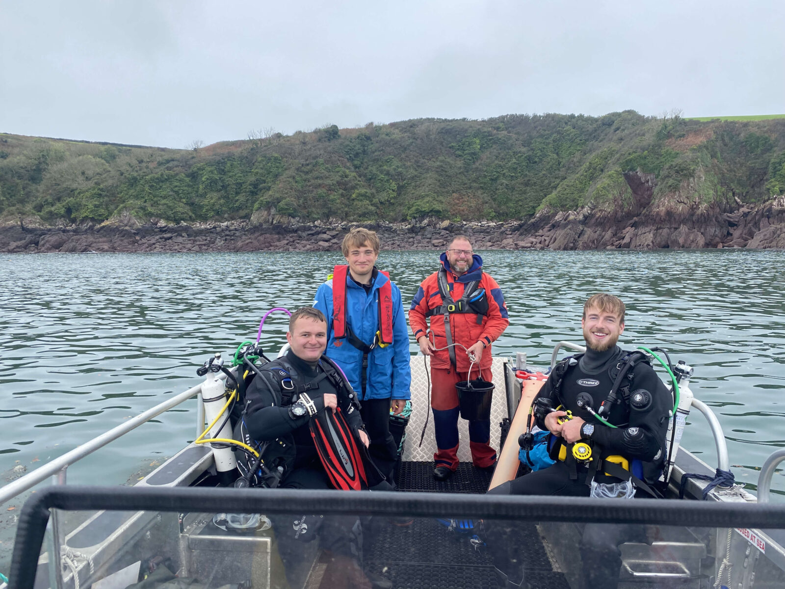 Volunteer Neil is standing aboard the Project Seagrass boat alongside members of three other members of the dive team.