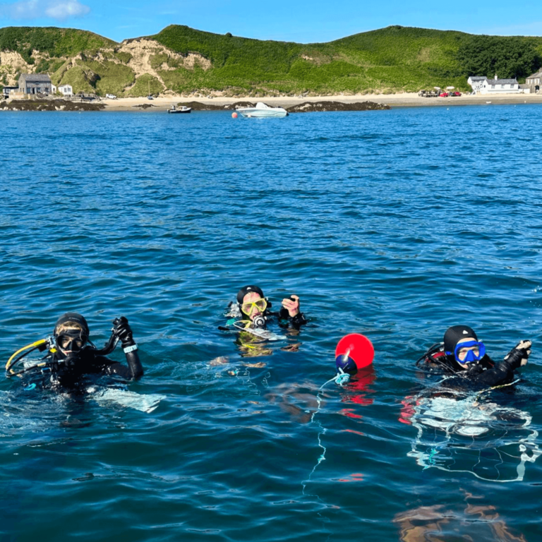 3 divers are in the sea in Porthdinllaen