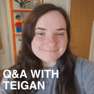 PhD student Teigan who is undertaking a PhD exploring the influence of water quality on greenhouse gas emissions. Teigan is seated with a bookshelf behind her. She is wearing a grey jumper and has long dark hair.