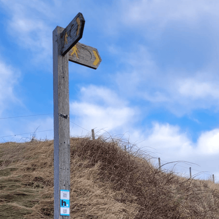 Signpost at Morfa Nefyn in North Wales with a HistoryPoints QR code where users can scan to learn more about the seagrass meadow in Porthdinllaen