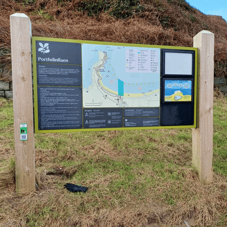 An information board with information about Porthdinllaen in North Wales. On the left hand pillar of the board is a QR code where users can scan to receive further information about the seagrass meadow in Porthdinllaen.