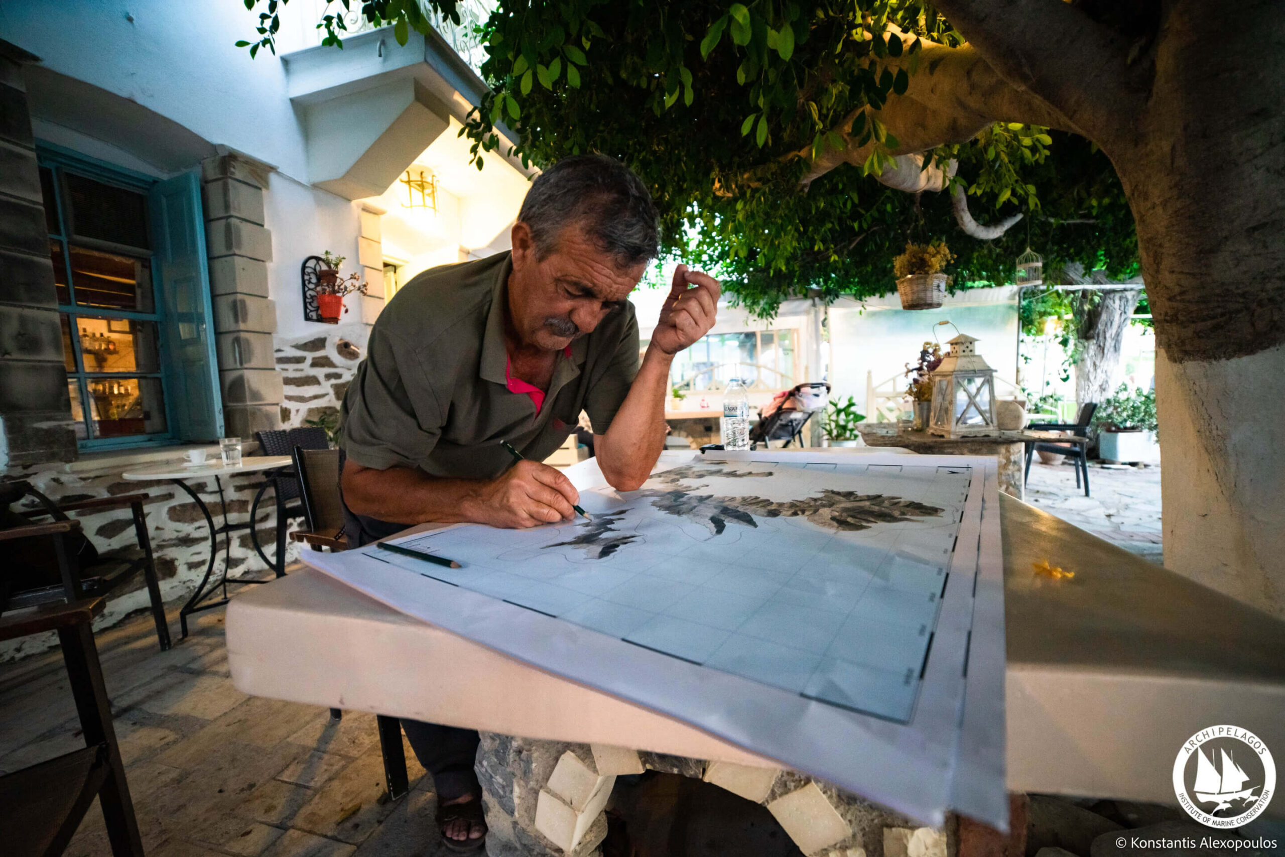 A fisher stands at a table with a map pinpointing where they believed seagrass beds could be found along the coastlines of their respective islands.
