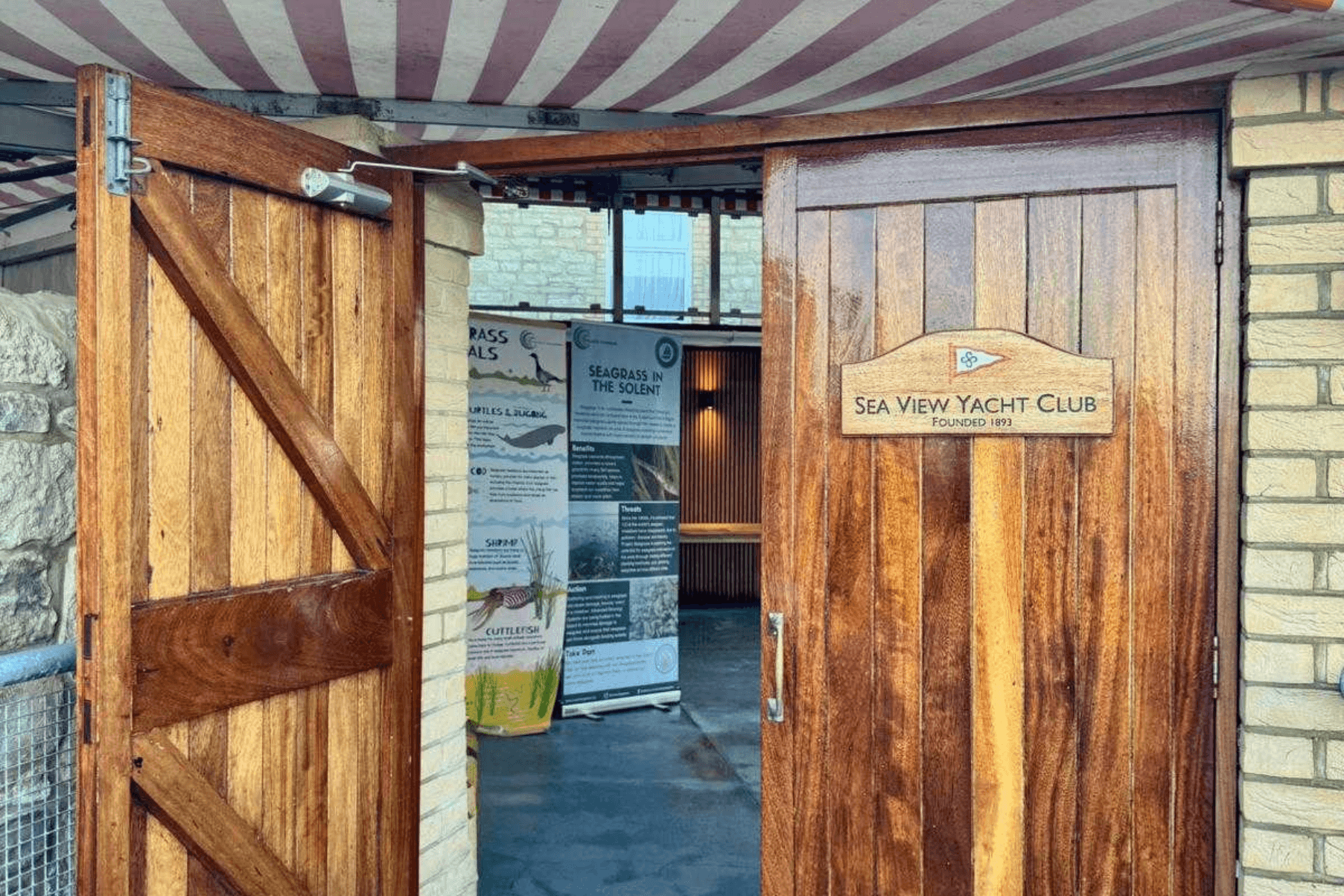 A door opens into Sea View Yacht Club. Inside are two Project Seagrass banners with information about the species that live in seagrass meadows and Project Seagrass' work in the Solent.