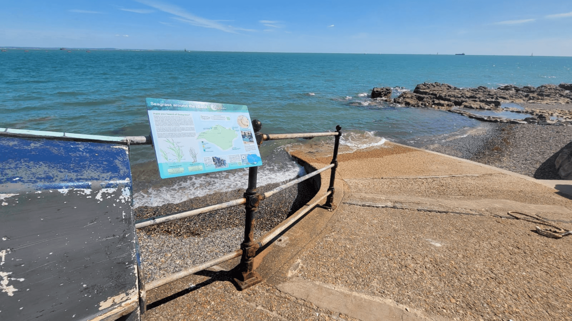 A sign with information about the Isle of Wight's seagrass meadows is attached to railings on the slipway at Seaview.