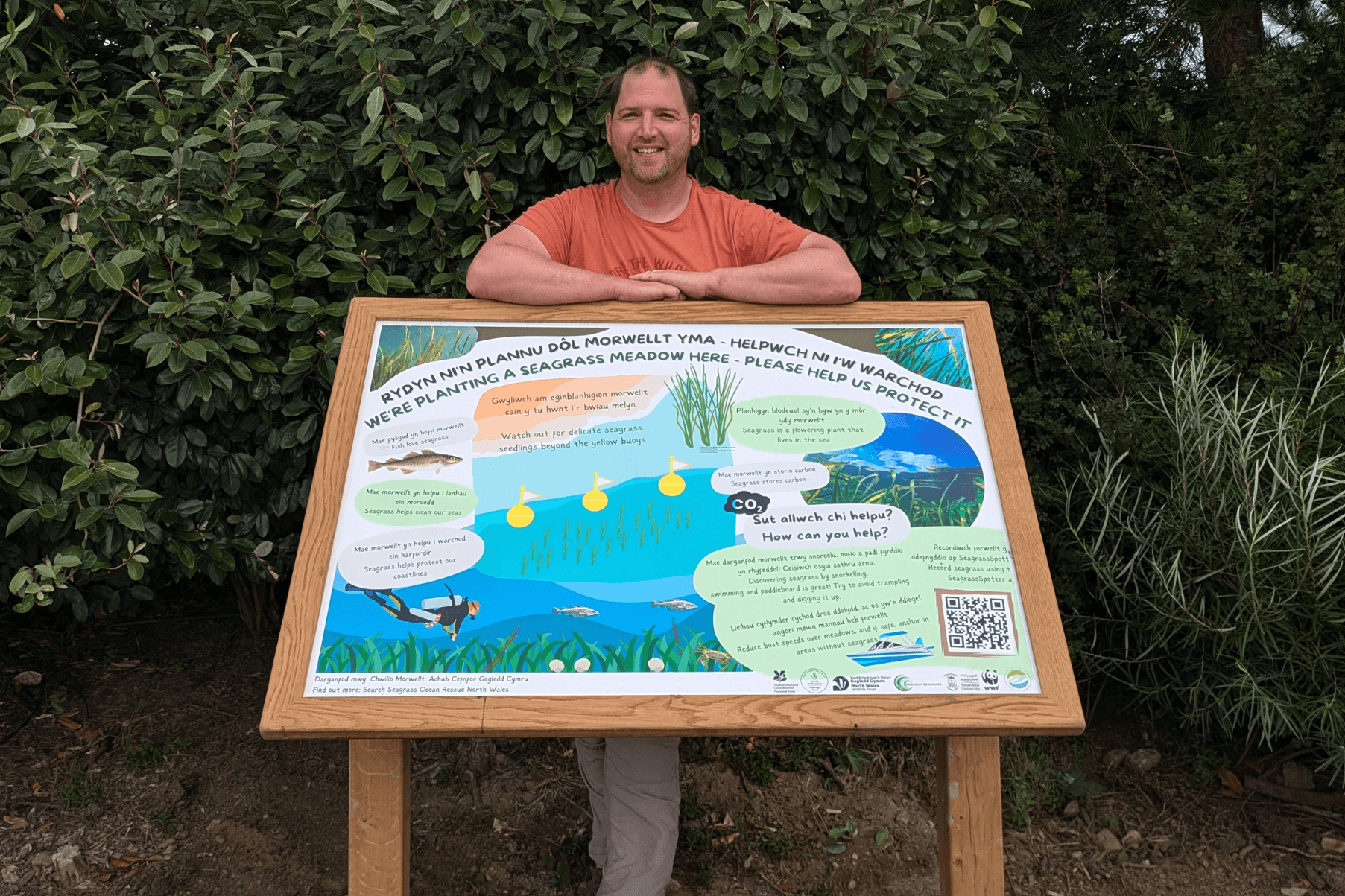 Andrew stands behind a newly installed sign providing information about local seagrass meadows.