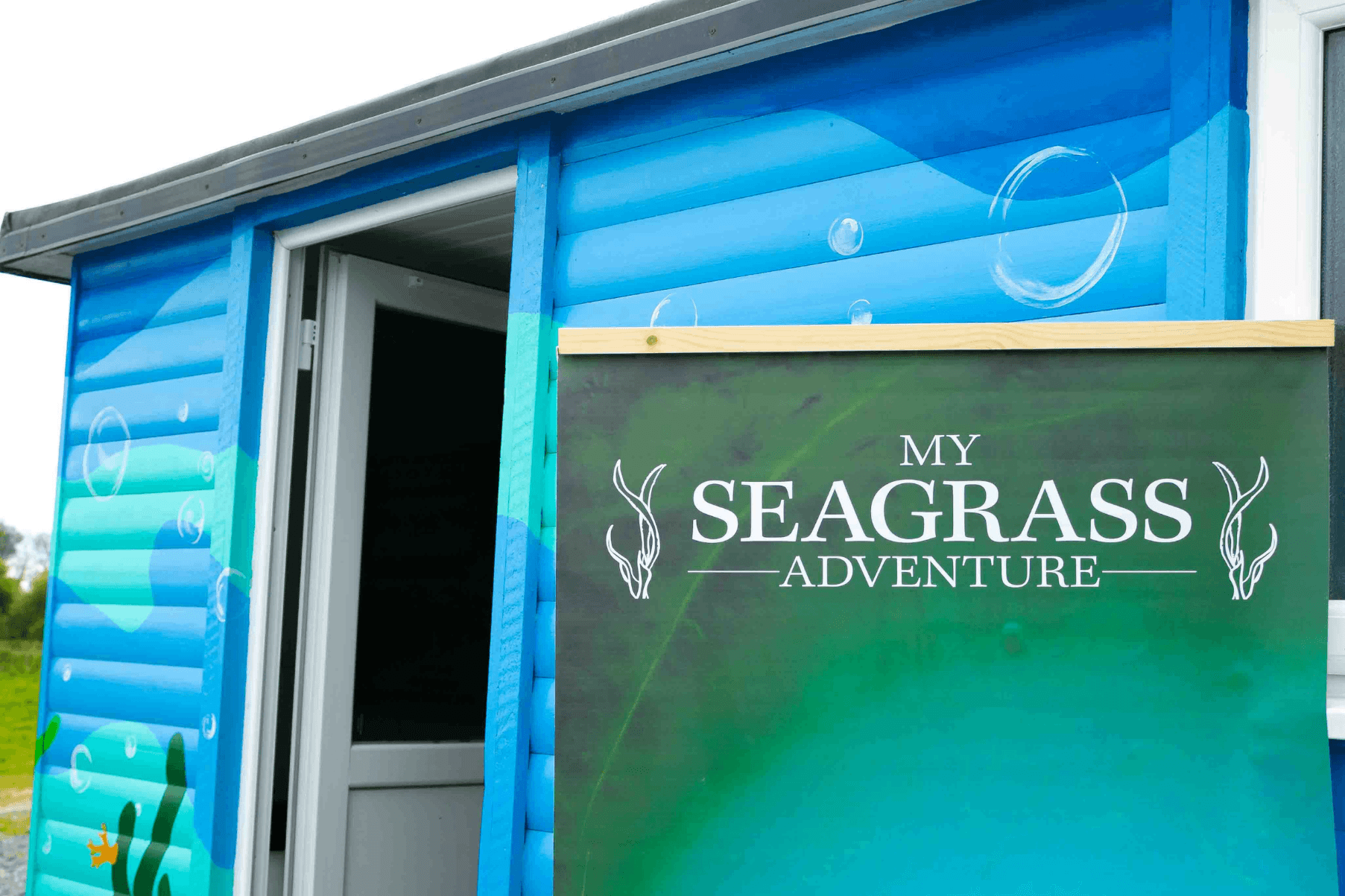 A banner advertising Project Seagrass' VR experience is placed outside a trailer.